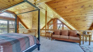 A loft-style bedroom with a bed, a wooden ceiling, a window, a sofa, and a small table. - 3-acre Benezette Cabin: Hot Tub, Grill & Mtn View (Benezette)