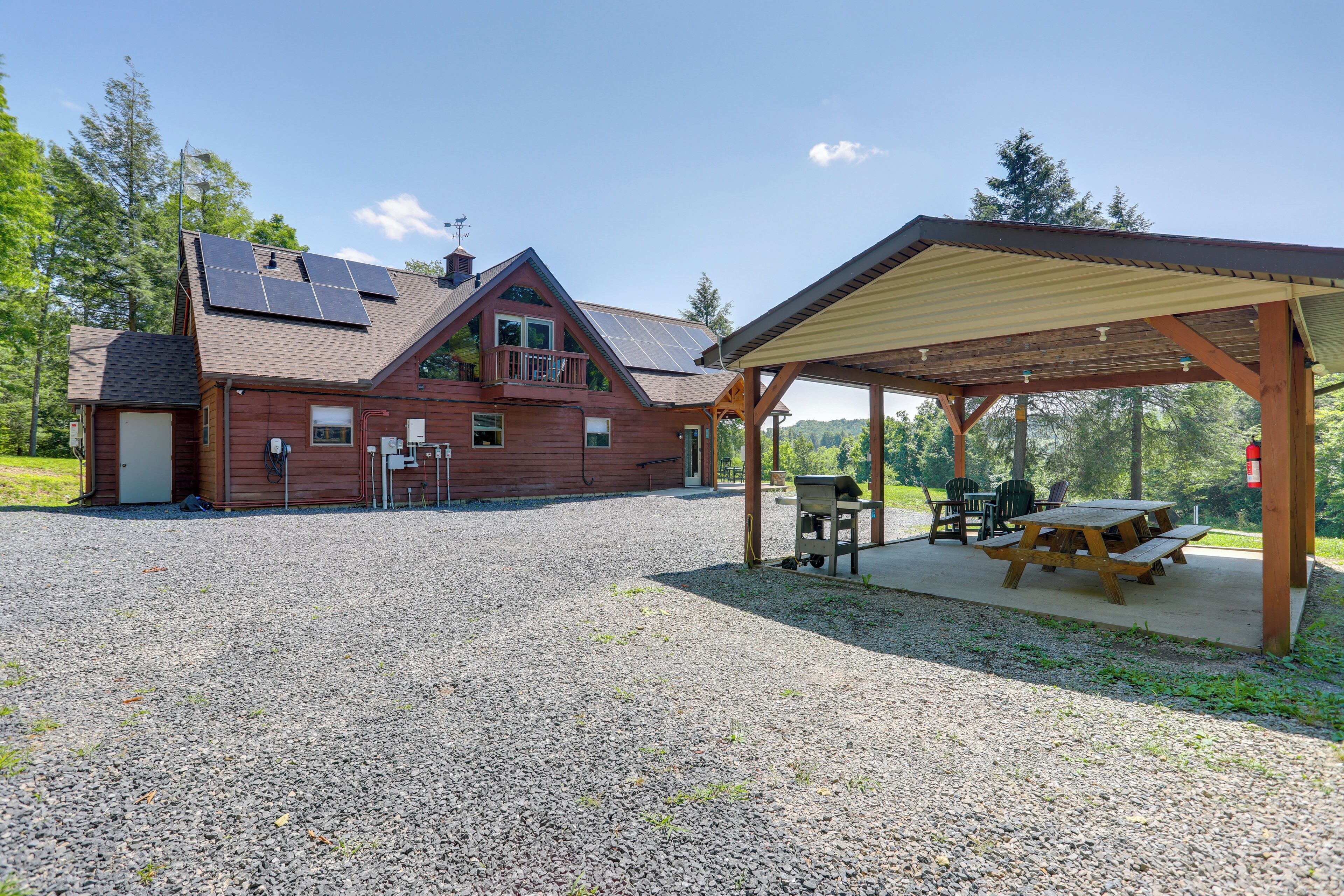 A lodge with a covered outdoor seating area, a garage, and solar panels on the roof.