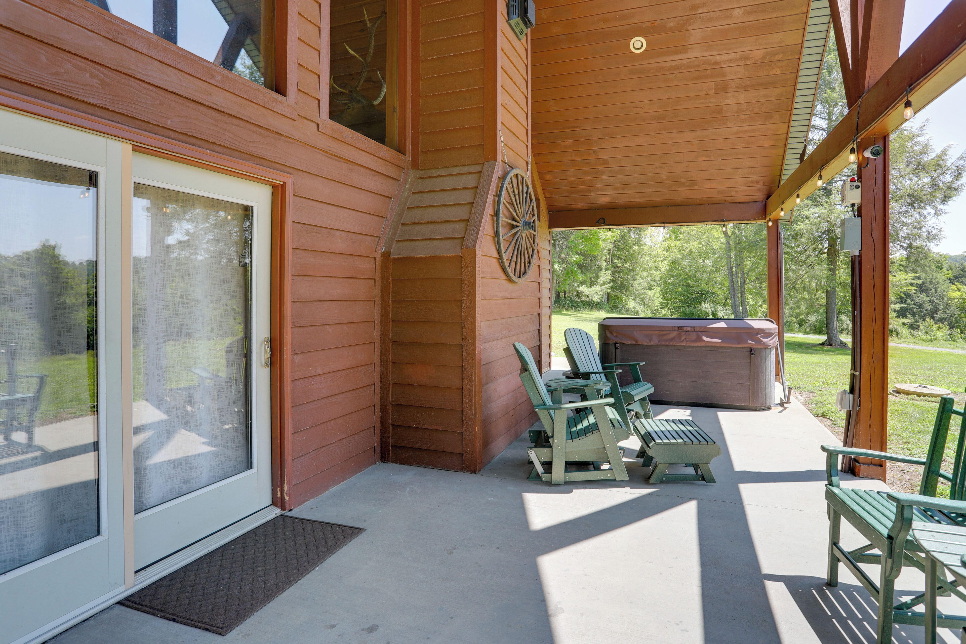 A covered outdoor area with a patio table and chairs, a hot tub, and a wooden deck.