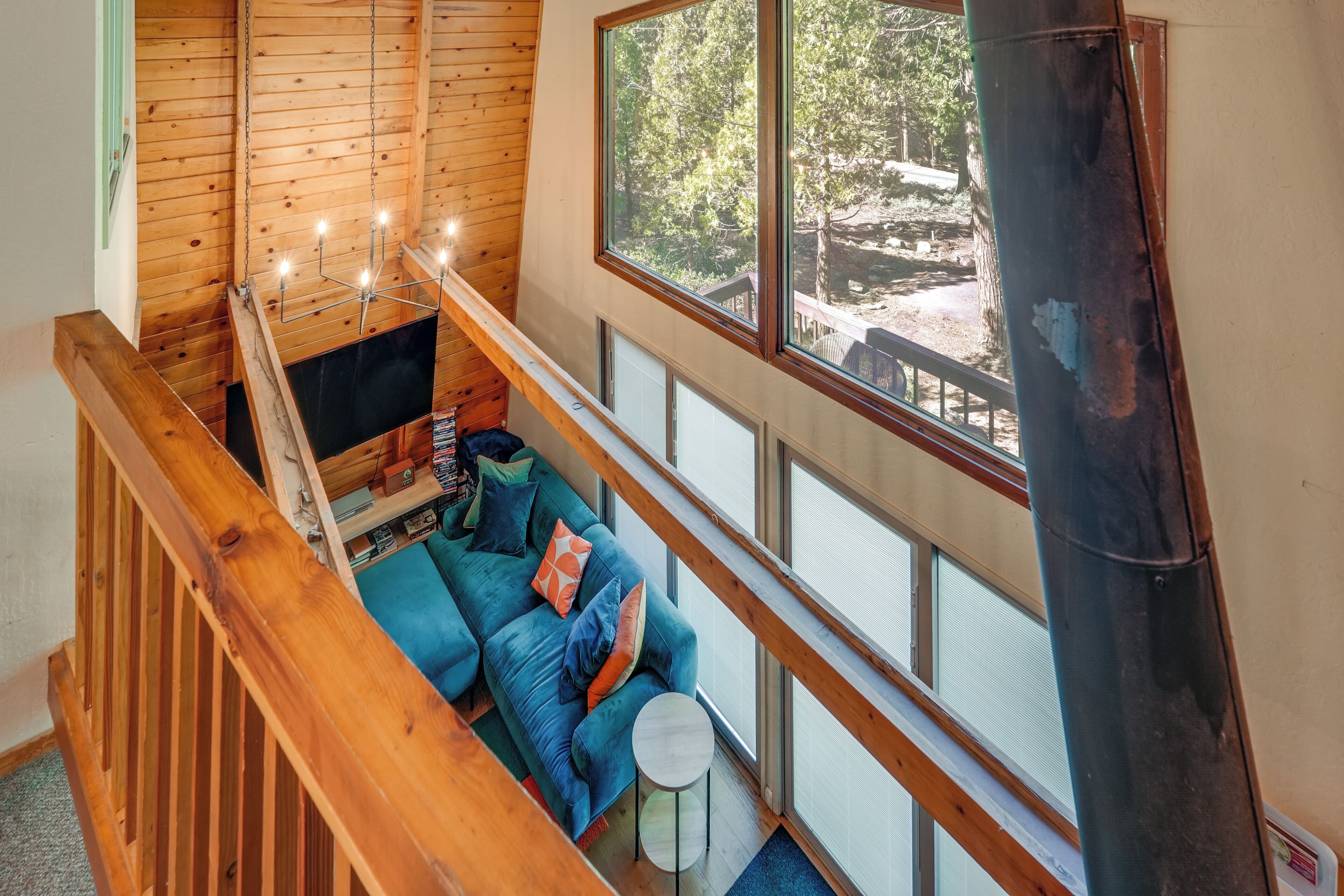 A wooden interior with a blue sofa, a small round table, and a wooden staircase.