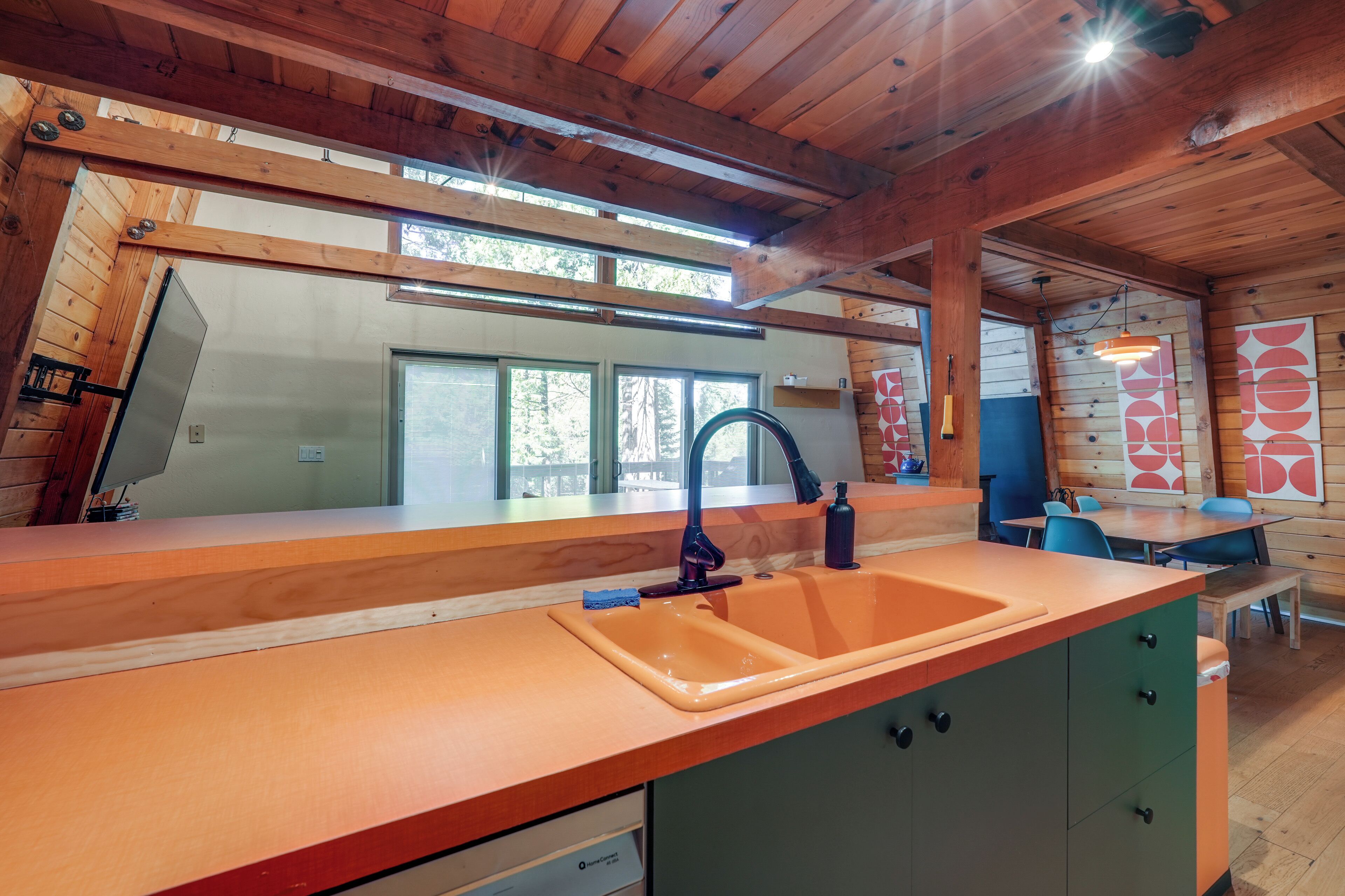 A modern kitchen with wooden beams, a large window, and a sink.