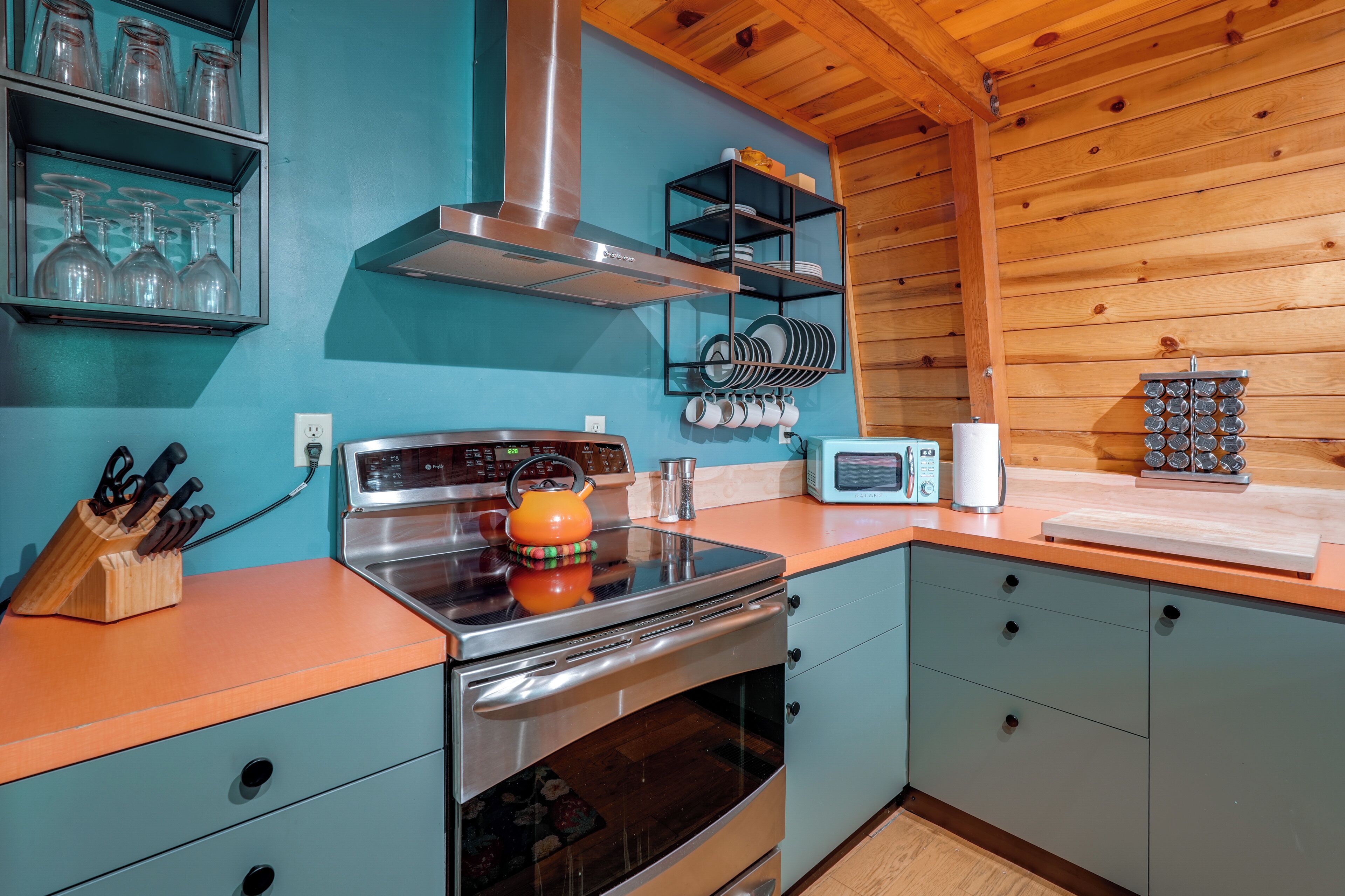 A kitchen with a stainless steel stove, a microwave, and a wooden ceiling.