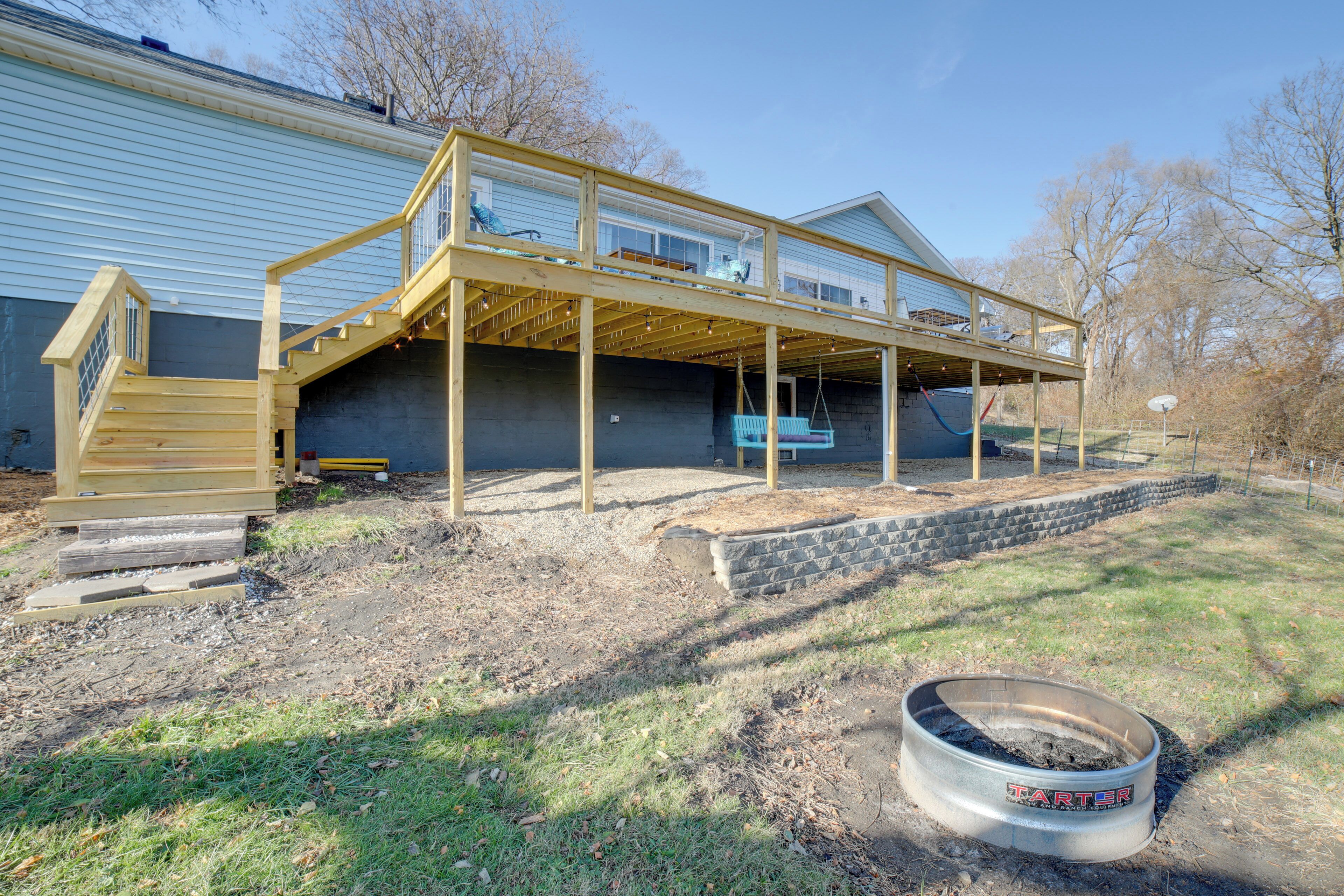 A house with a wooden deck, a staircase, and a basketball hoop.