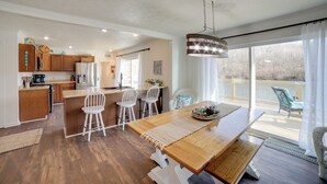 Une cuisine spacieuse avec des meubles en bois, un îlot central et des chaises blanches.