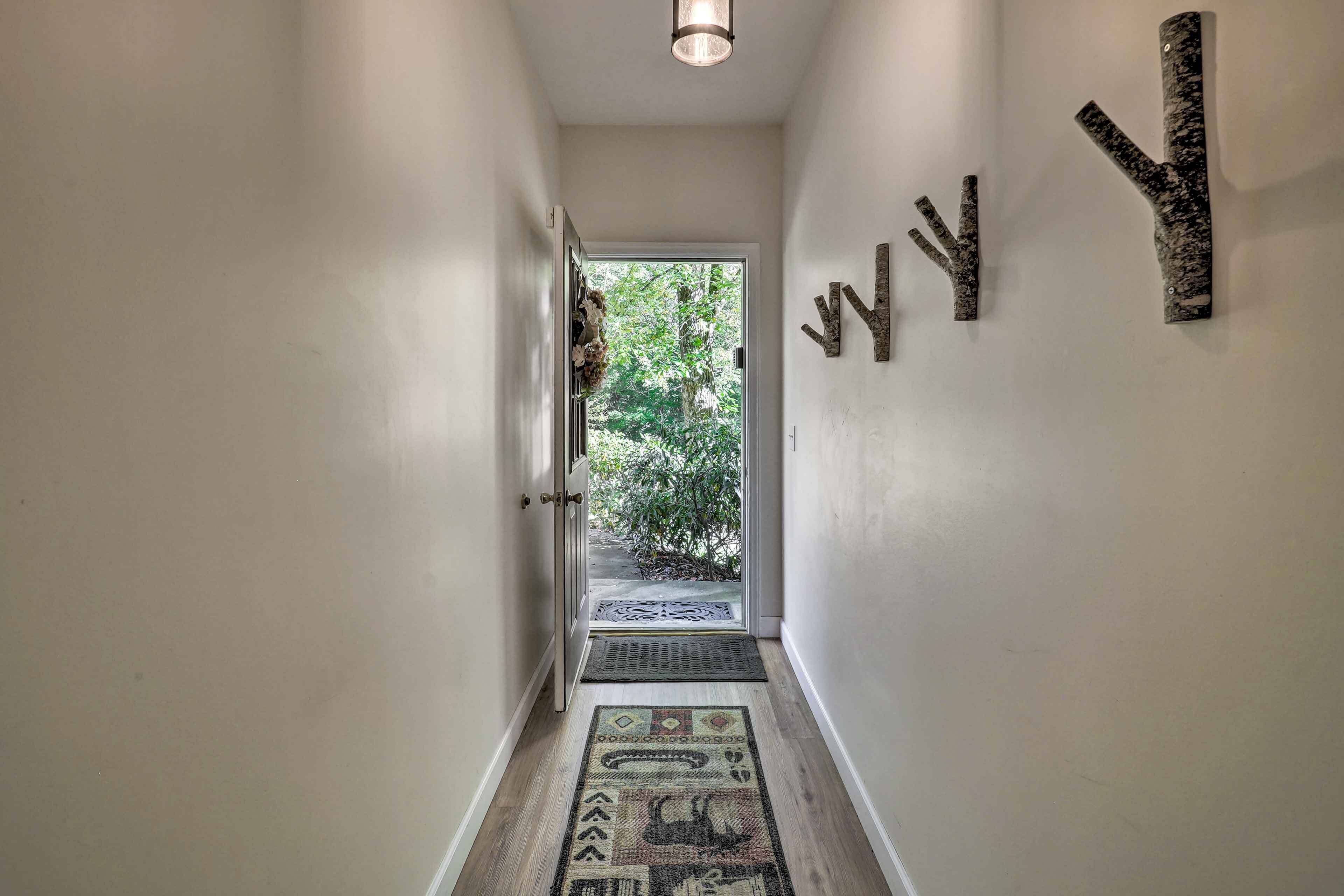 A hallway with a door leading to a garden, a patterned rug, and wall-mounted decor.