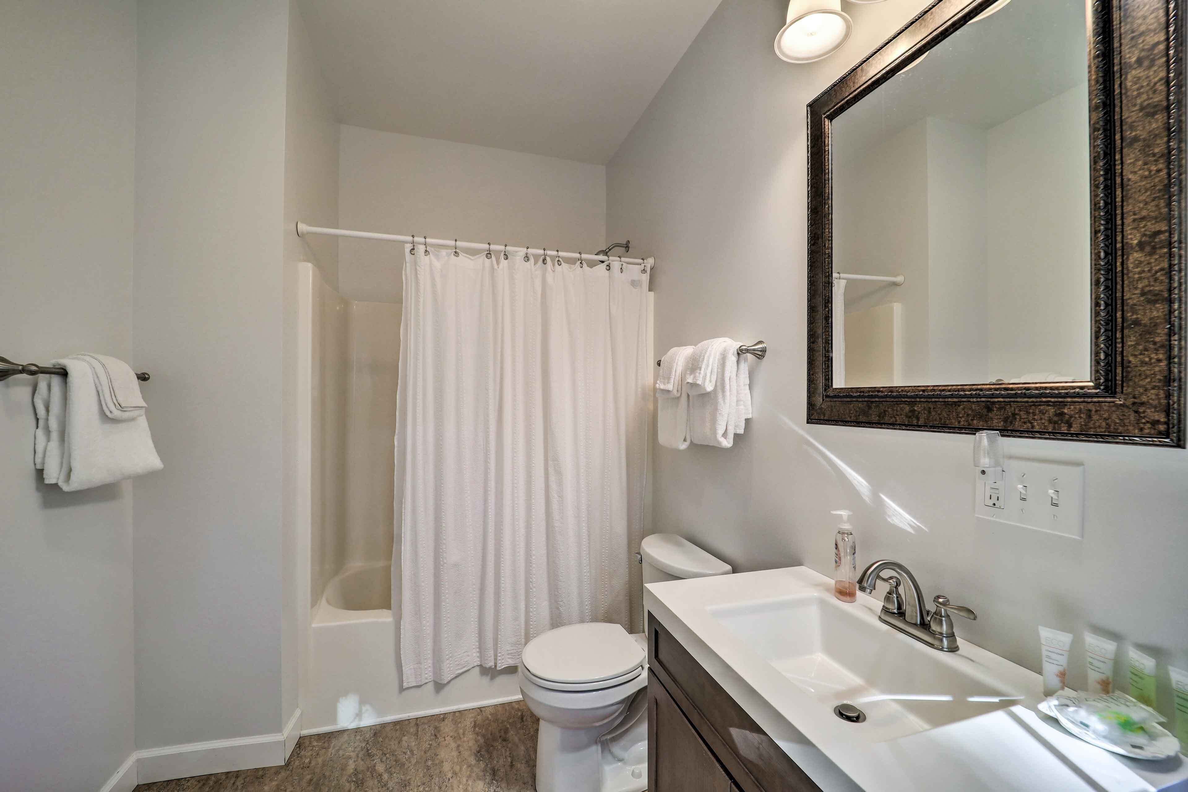 A bathroom with a bathtub, toilet, sink, and a large mirror.