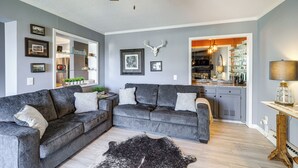A modern living room with grey sofas, a black and white rug, and a kitchen visible through an open doorway. - Resort Amenities: Beech Mtn Condo Near Skiing! (Banner Elk)
