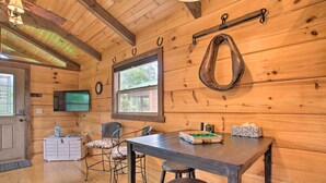 A wooden cabin interior with a dining table, two chairs, a television, and a small cabinet. - Near Winter Trails! Rustic Cabin in Mill Spring (Mill Spring)