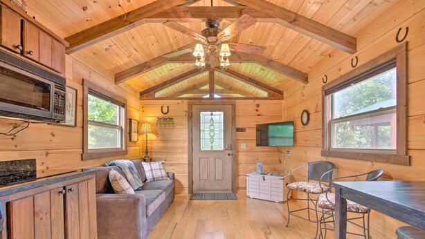 A cozy cabin interior with wooden walls, a kitchen area, a dining table, and a comfortable seating area. - Near Winter Trails! Rustic Cabin in Mill Spring (Mill Spring)