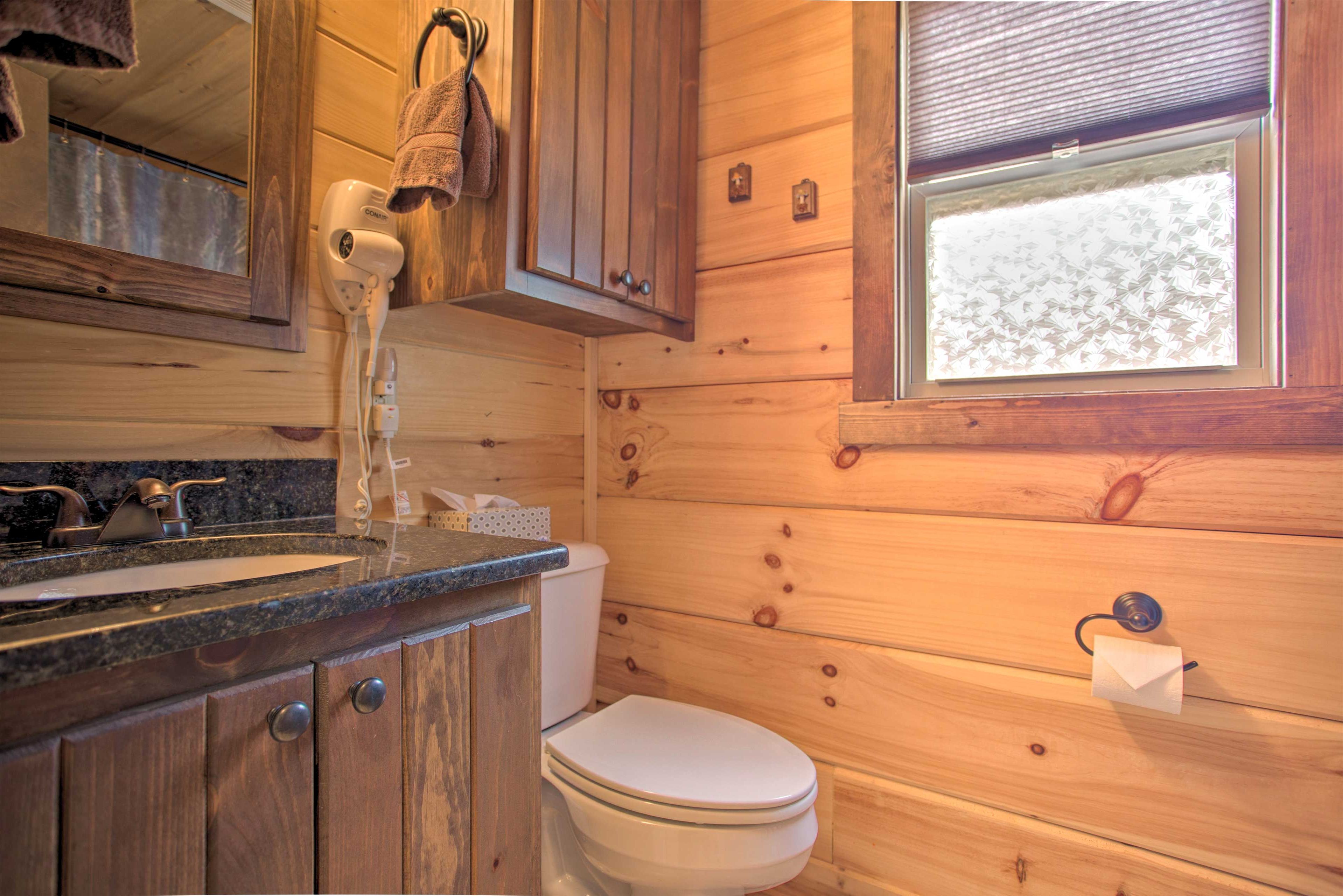 Une salle de bain rustique, aménagée dans une cabane en bois, avec un lavabo, des toilettes et une fenêtre.