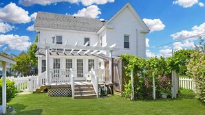 A white two-story house with a covered porch and a fenced yard. - 'chincoteague Charm' Escape w/ Bikes & Yard Games! (Chincoteague)