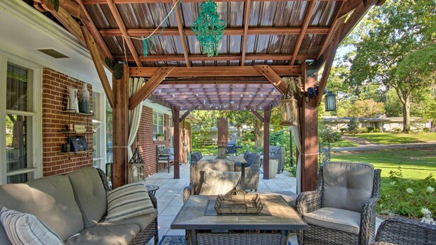 A covered patio with wicker furniture, a brick wall, and a view of the garden. - Charming Florence Getaway w/ Fireplace & Grill! (Florence)