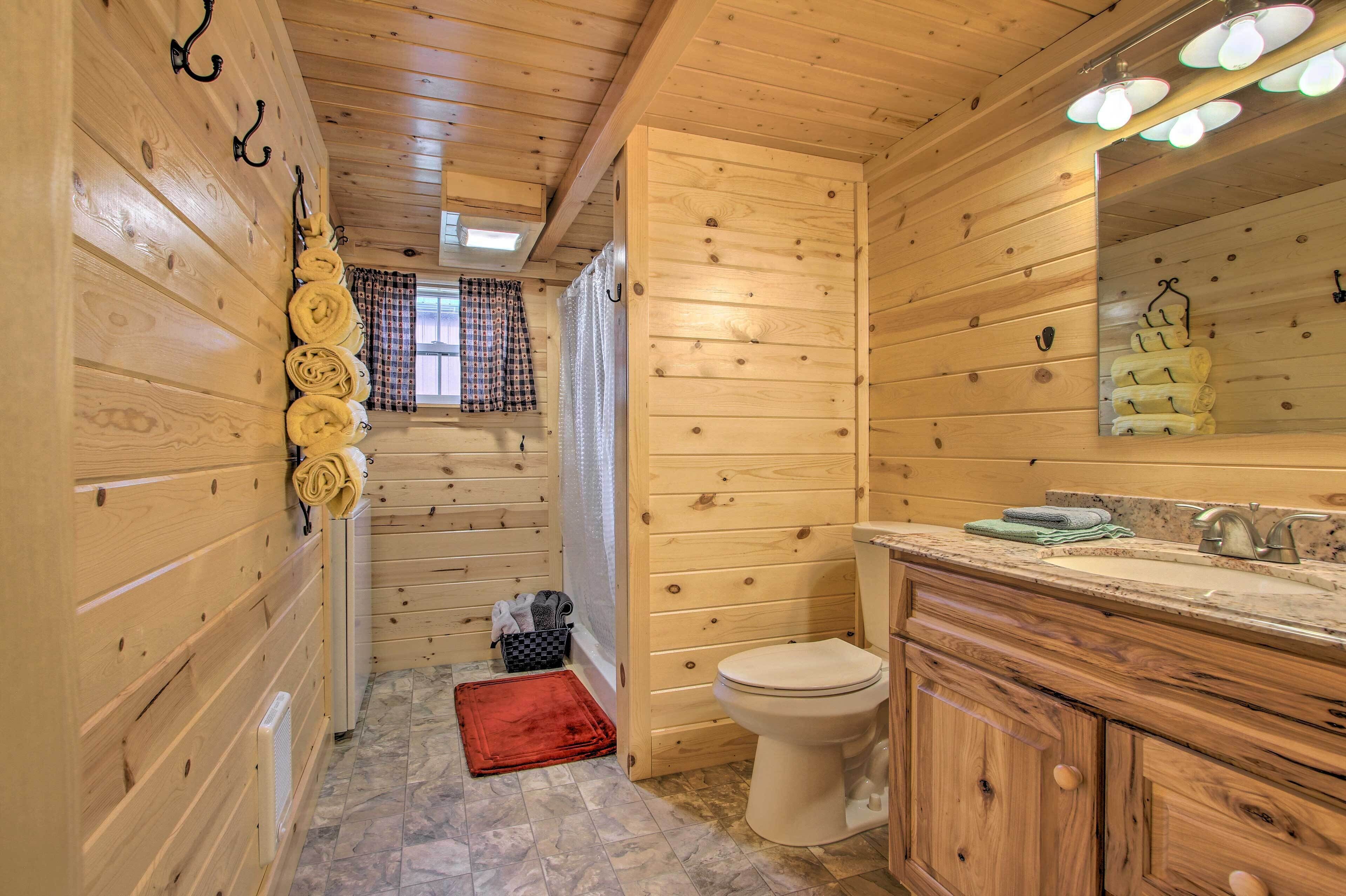 A wooden cabin bathroom with a toilet, sink, and wooden cabinets.