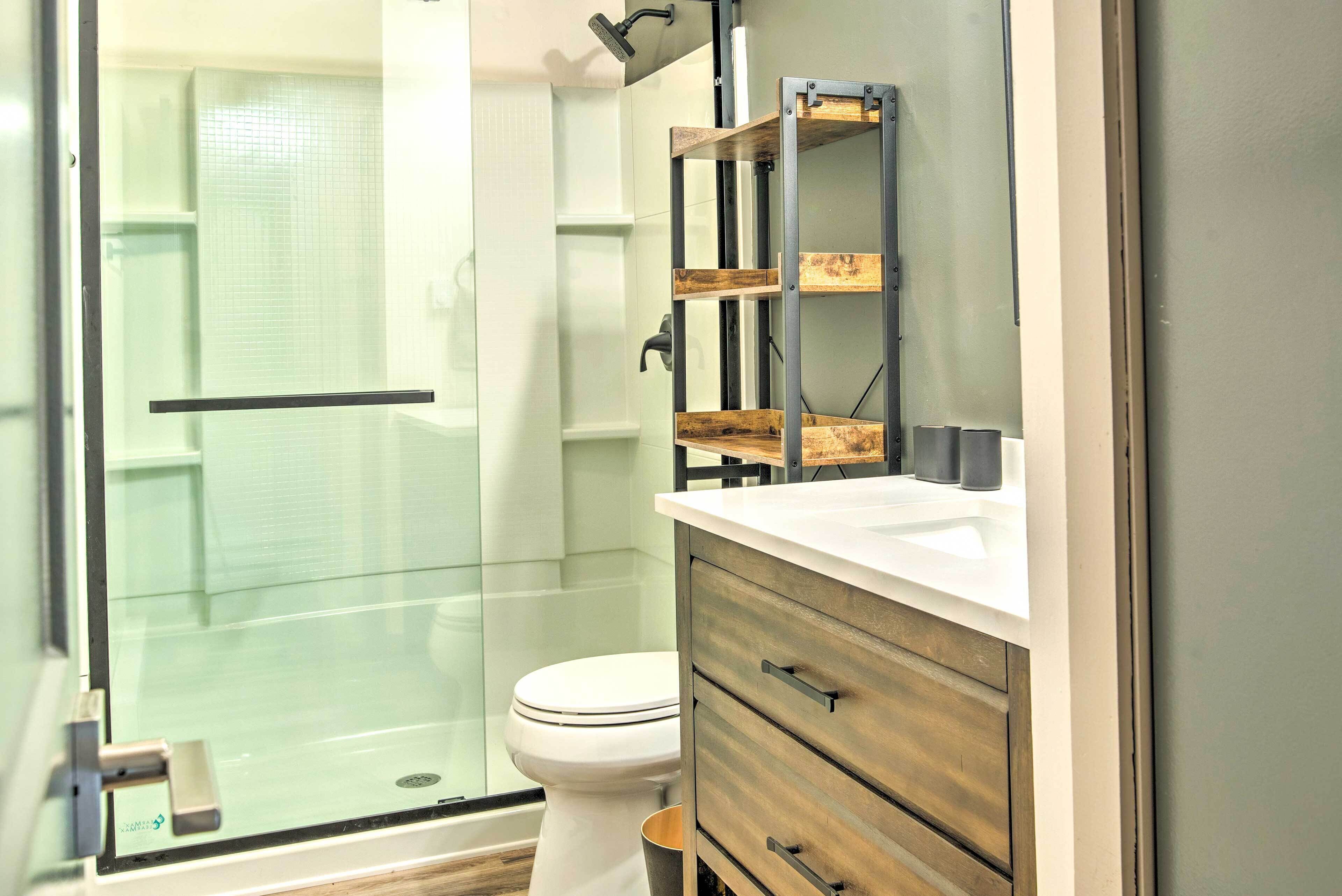 A modern bathroom with a glass shower enclosure, a white toilet, and wooden cabinetry.