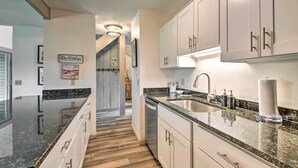 A modern kitchen with white cabinets, granite countertops, and a wooden floor. There is a sink with a faucet and a dish rack. - Cortland Abode: 1 Mi to Greek Peak Mountain Resort (Cortland)
