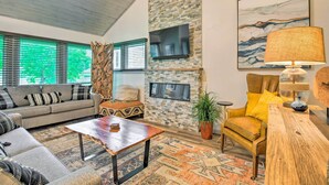 A living room with a stone fireplace, a sofa, a coffee table, and a yellow armchair. - Cortland Abode: 1 Mi to Greek Peak Mountain Resort (Cortland)