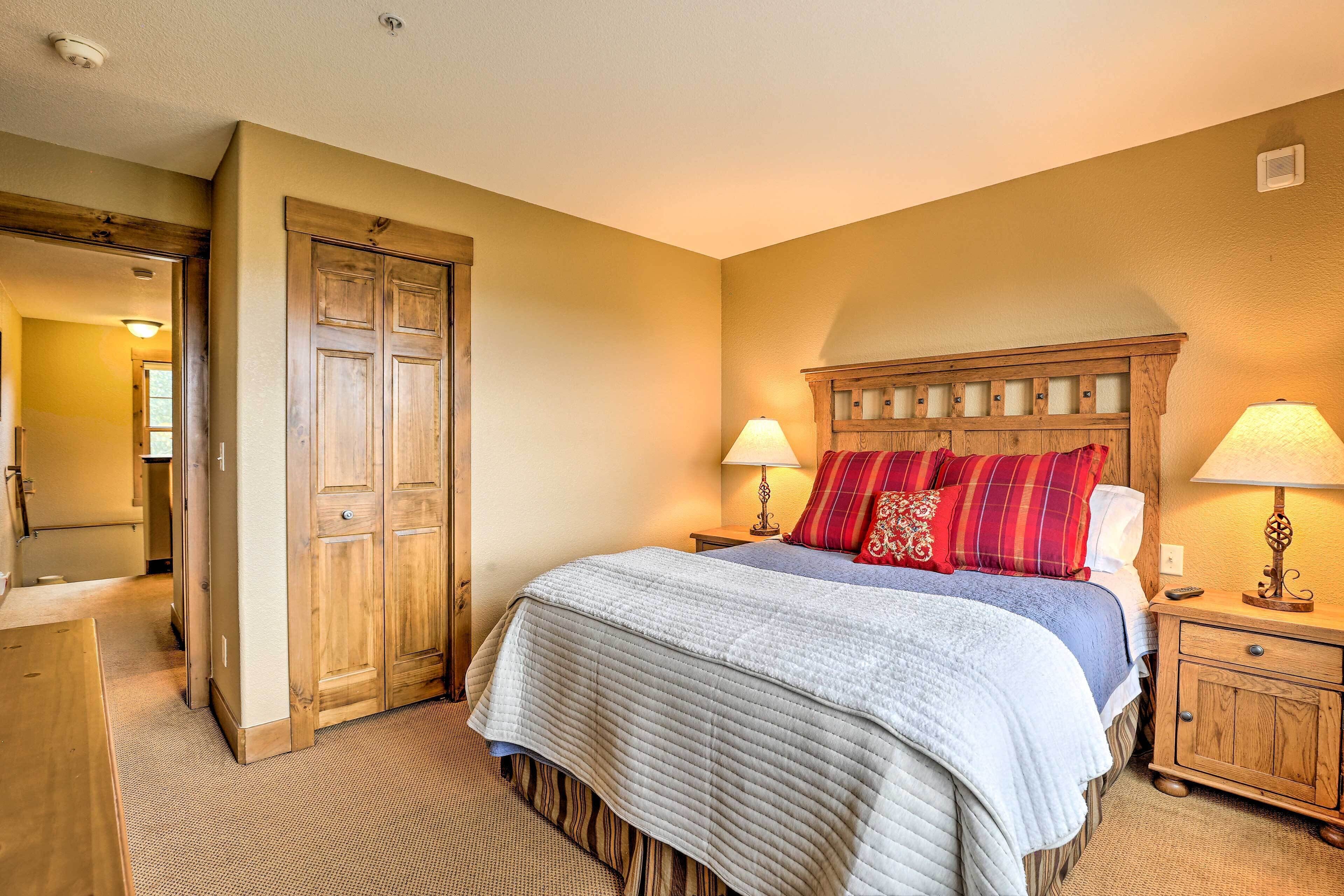 A bedroom with a large bed, wooden headboard, two bedside tables with lamps, and a wardrobe.