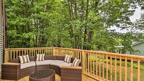 Une terrasse en bois avec un canapé en rotin marron aux lignes courbes et une table ronde en rotin.