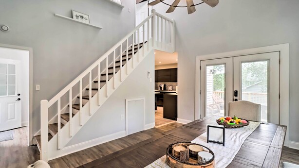 Un intérieur moderne avec un escalier, un coin repas où une table est dressée pour le repas, et une cuisine en arrière-plan.