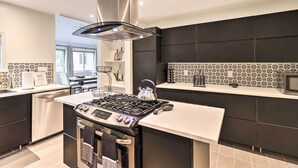Une cuisine moderne dotée d’un îlot central, d’appareils électroménagers en acier inoxydable et d’un dosseret décoratif.
