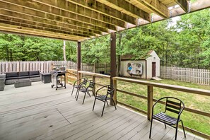 A covered deck with outdoor furniture, a grill, and a birdhouse.