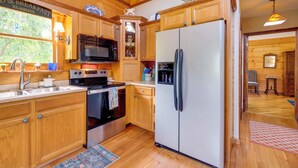 A kitchen with wooden cabinets, a refrigerator, a microwave, and a stove.