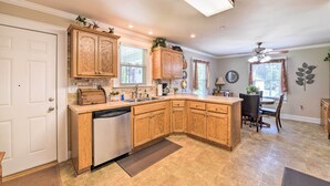 A kitchen with wooden cabinets, a dishwasher, and a dining area with a table and chairs.