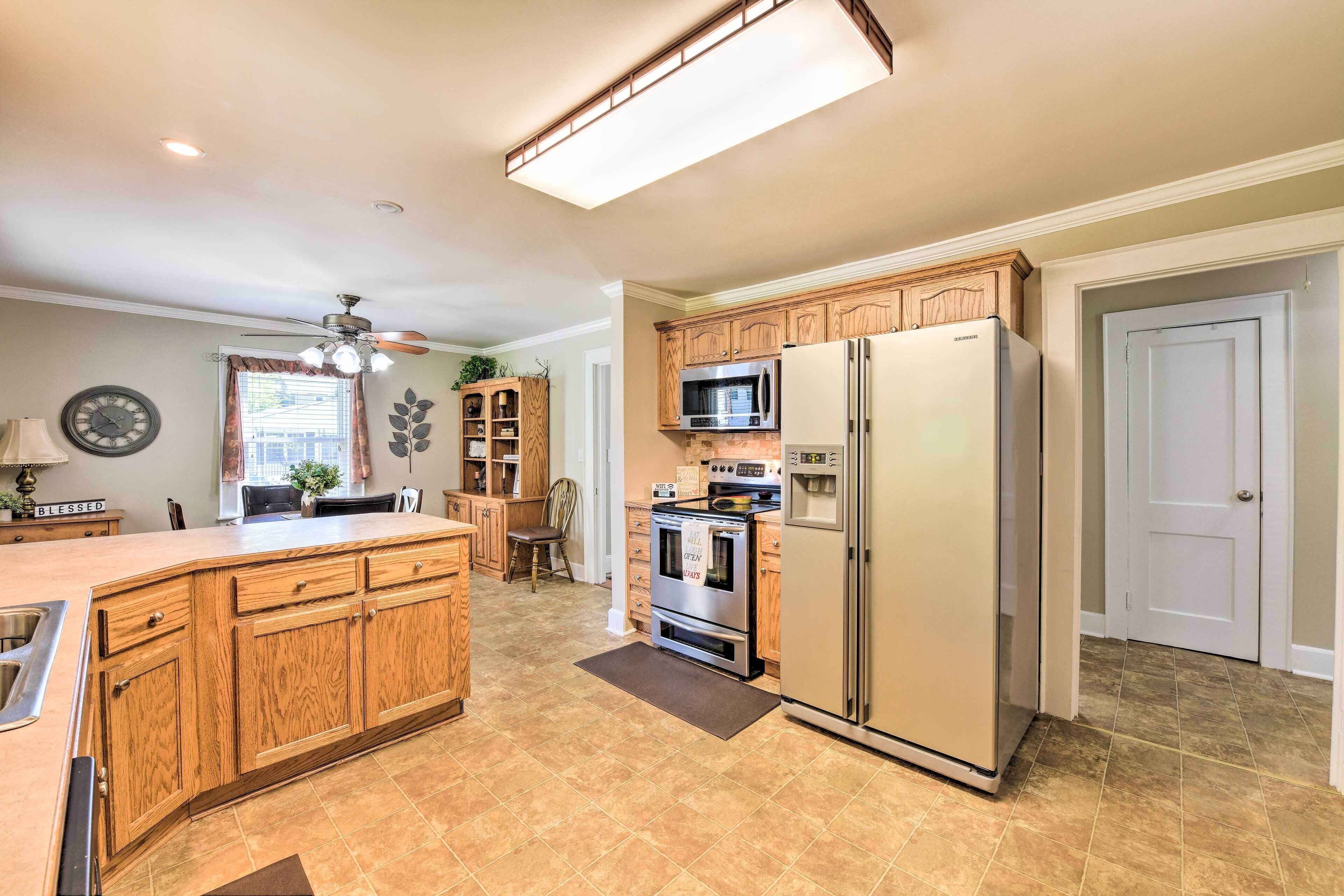 A kitchen with wooden cabinets, a stainless steel refrigerator, a microwave, and an oven.