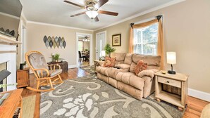 A living room with a beige sofa, a rocking chair, a coffee table, a side table with a lamp, and a ceiling fan.