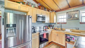 Een moderne keuken met roestvrijstalen apparatuur, houten kasten en een rustiek plafond.