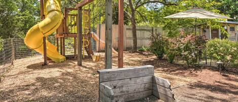 A playground with a yellow slide and a wooden bench.