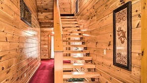 Un intérieur en bois avec un escalier, des murs en bois et une moquette rouge.