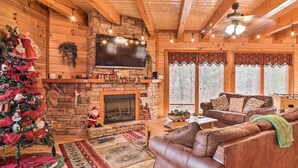 L’intérieur chaleureux d’un chalet en bois, avec une cheminée, un canapé en cuir et un sapin de Noël.
