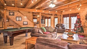 L’intérieur d’un chalet confortable, avec une table de billard, des canapés en cuir, une table à manger et un sapin de Noël.
