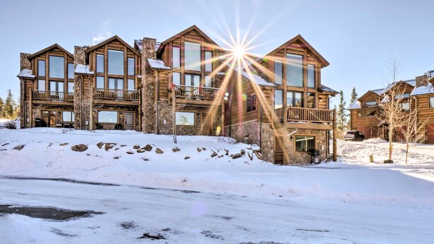 Un chalet à plusieurs étages, doté d’une façade en pierre, de grandes fenêtres et d’un balcon à l’étage supérieur.
