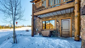 Un bâtiment en pierre doté d’un balcon en bois, d’une entrée couverte et d’un sol recouvert de neige.