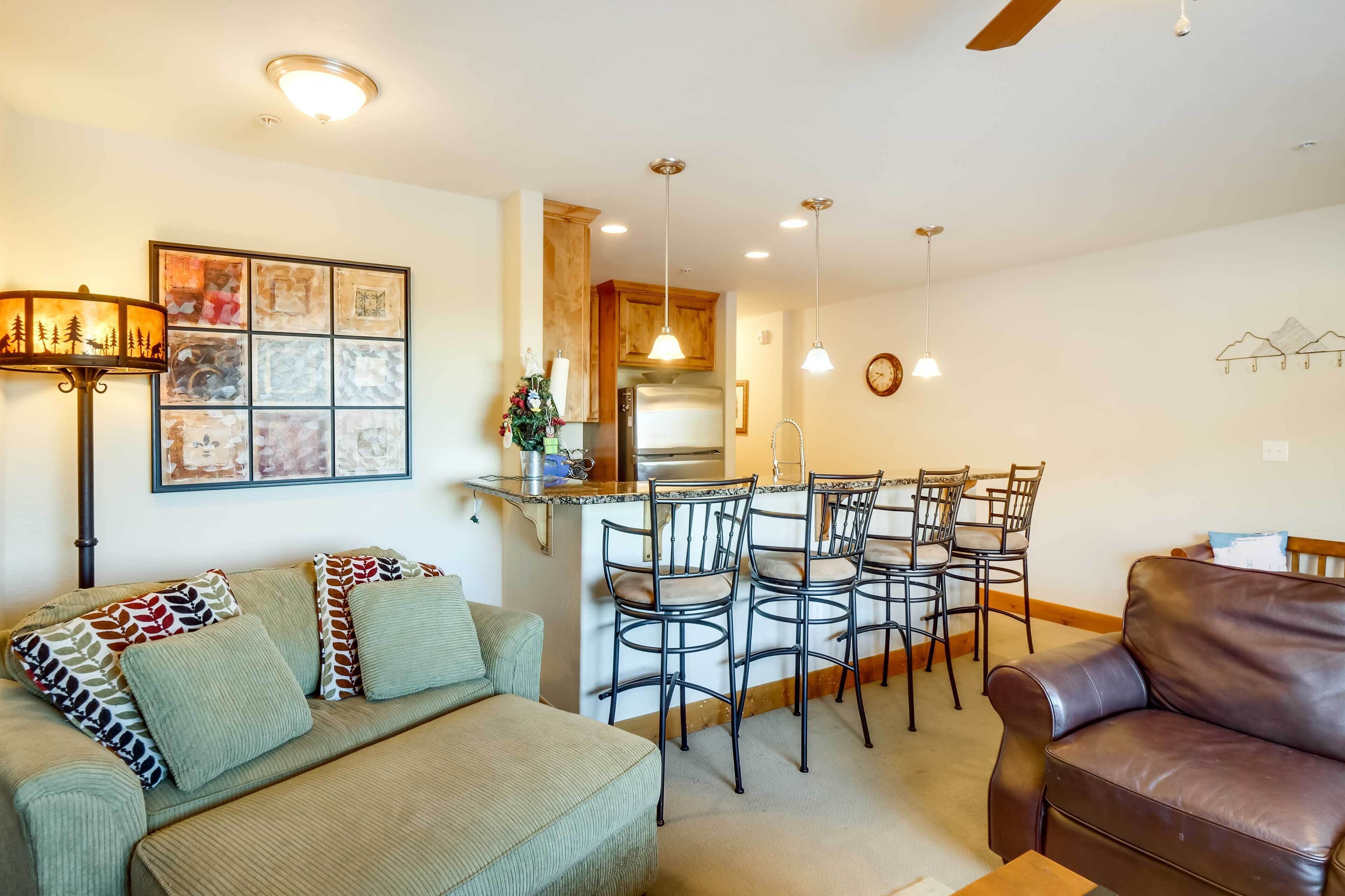 A living room with a sofa, a coffee table, and a dining area with chairs and a kitchen in the background.