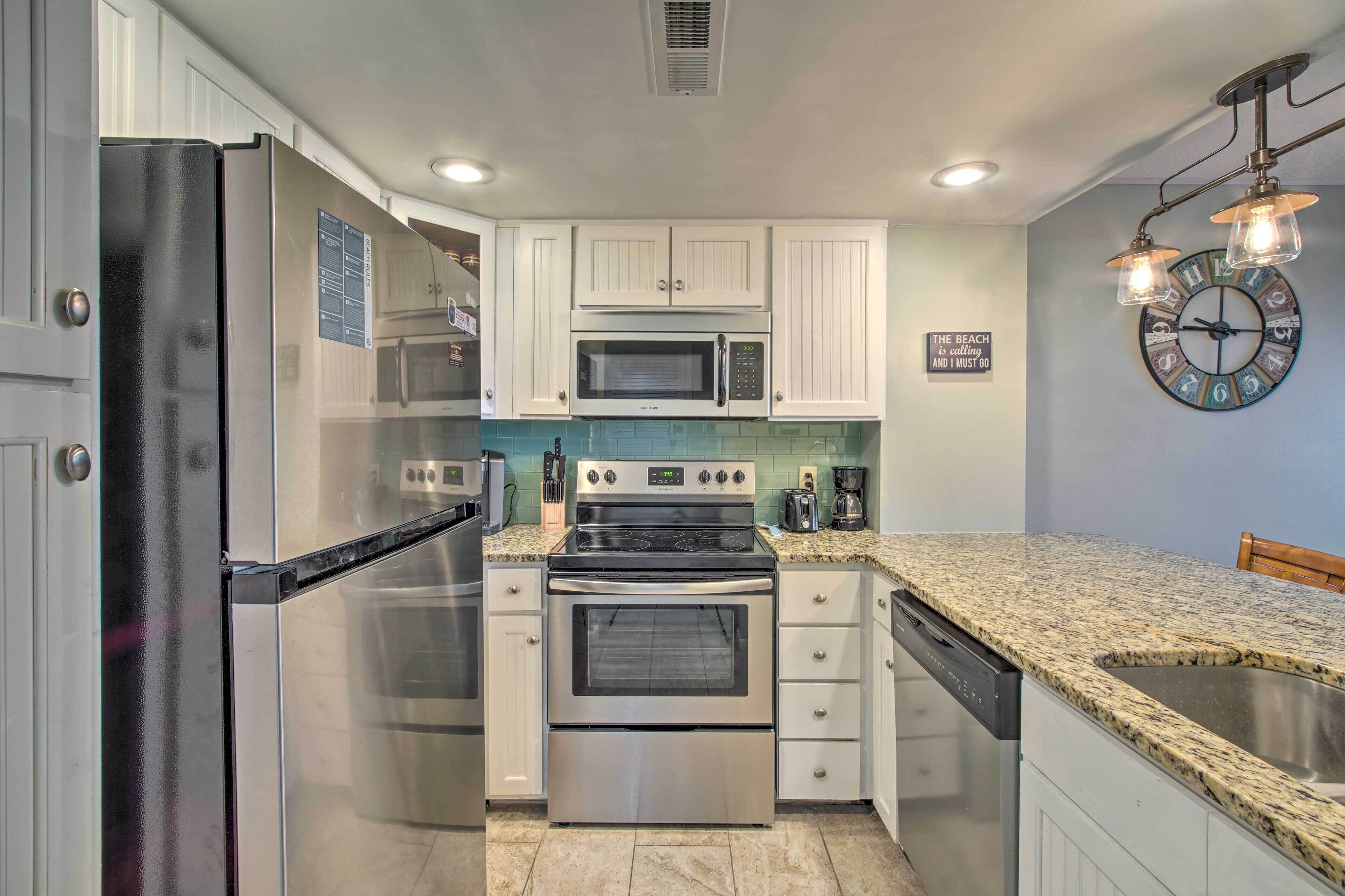 A kitchen with stainless steel appliances, white cabinets, a granite countertop, and a clock on the wall.