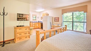 A bedroom with a large bed, wooden dresser, and a view of the kitchen through a window. - Bright Davis Escape w/ Screened-in Porch! (Davis)