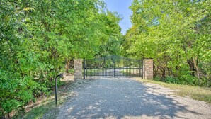 A gravel path leading to a gated entrance surrounded by lush green trees. - Bright Davis Escape w/ Screened-in Porch! (Davis)