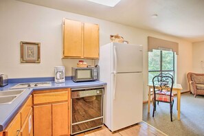 A compact kitchen with wooden cabinets, a microwave, a refrigerator, and a dishwasher.
