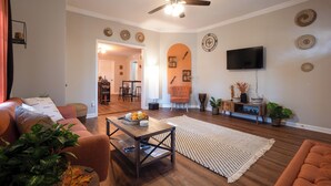 A living room with a sofa, coffee table, and a TV mounted on the wall. - Charming Huntsville Home w/ Deck! (Huntsville)