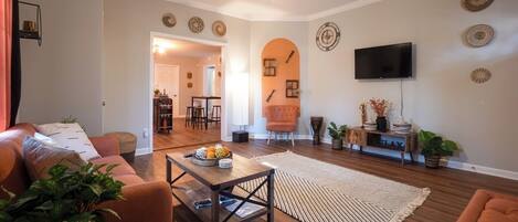 A living room with a sofa, coffee table, and a TV mounted on the wall.