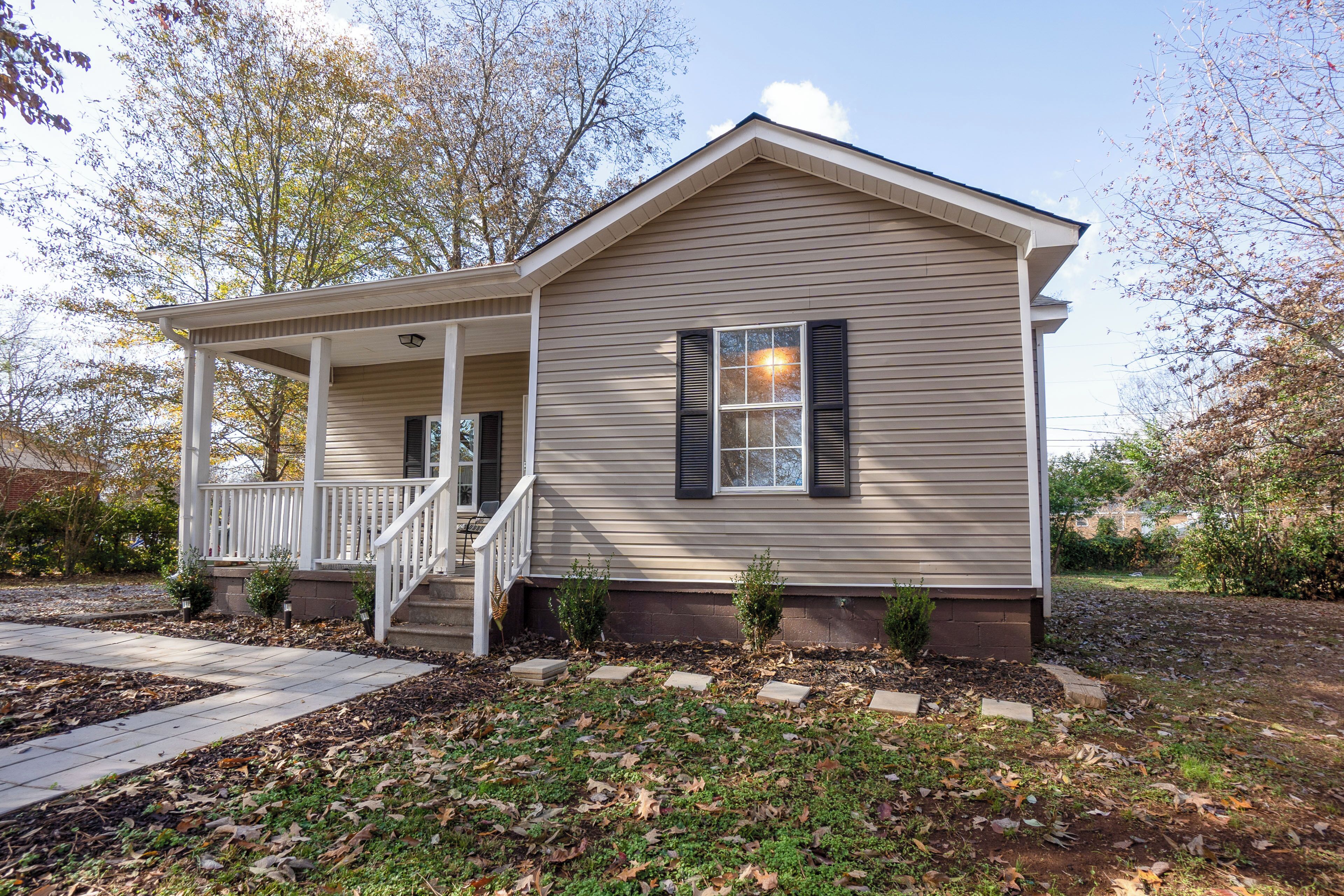 A single-story house with a front porch, a staircase leading to the entrance, and a small front yard with a pathway.