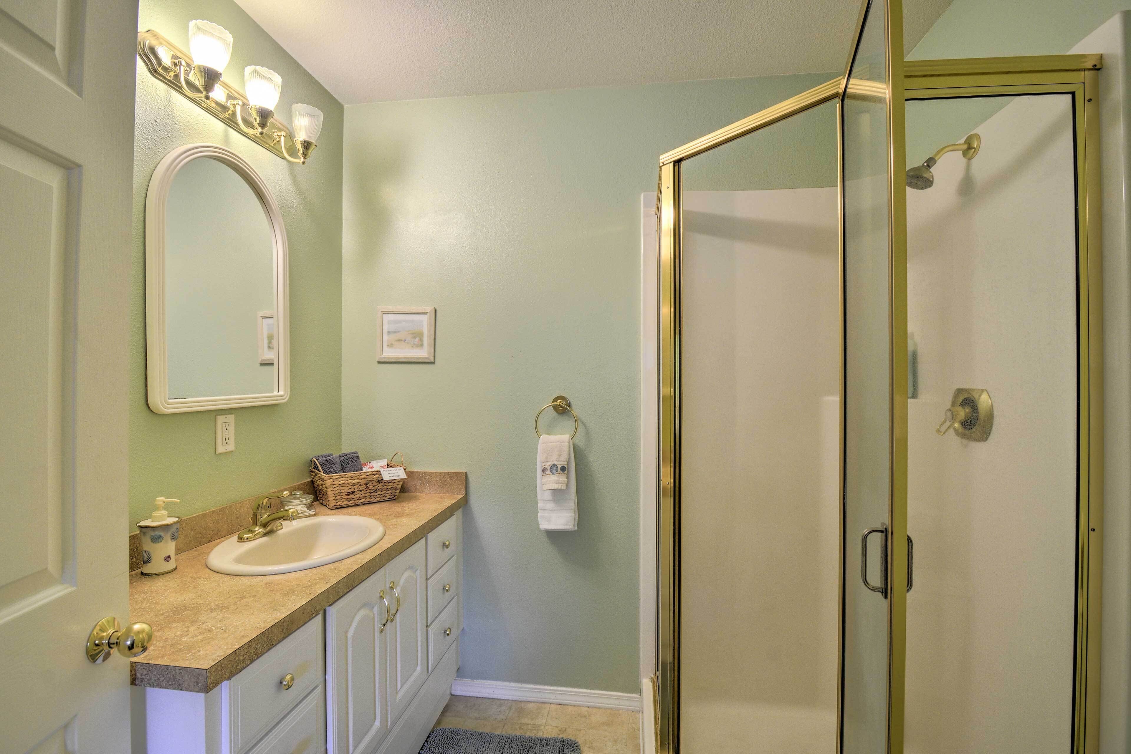 A bathroom with a sink, mirror, and shower.