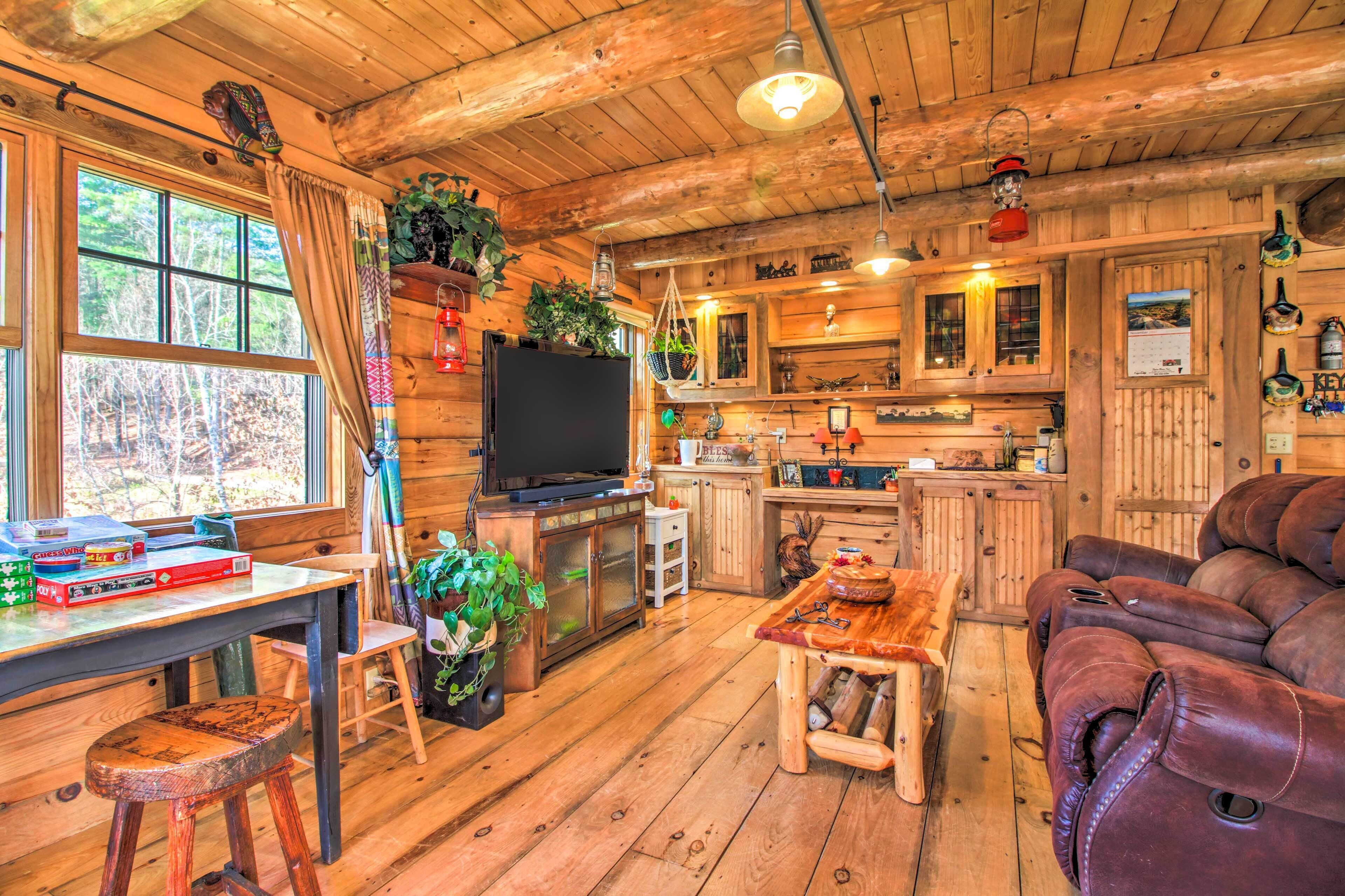 Ein rustikales Blockhaus-Interieur mit einem Holzespeisesaal, einer Couch, einem Fernseher und einer Küchenzeile.
