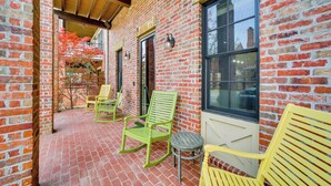 A brick exterior with a covered patio area featuring rocking chairs and a small table. - Carlton Landing Retreat w/ Eufaula Lake Access! (Eufaula)