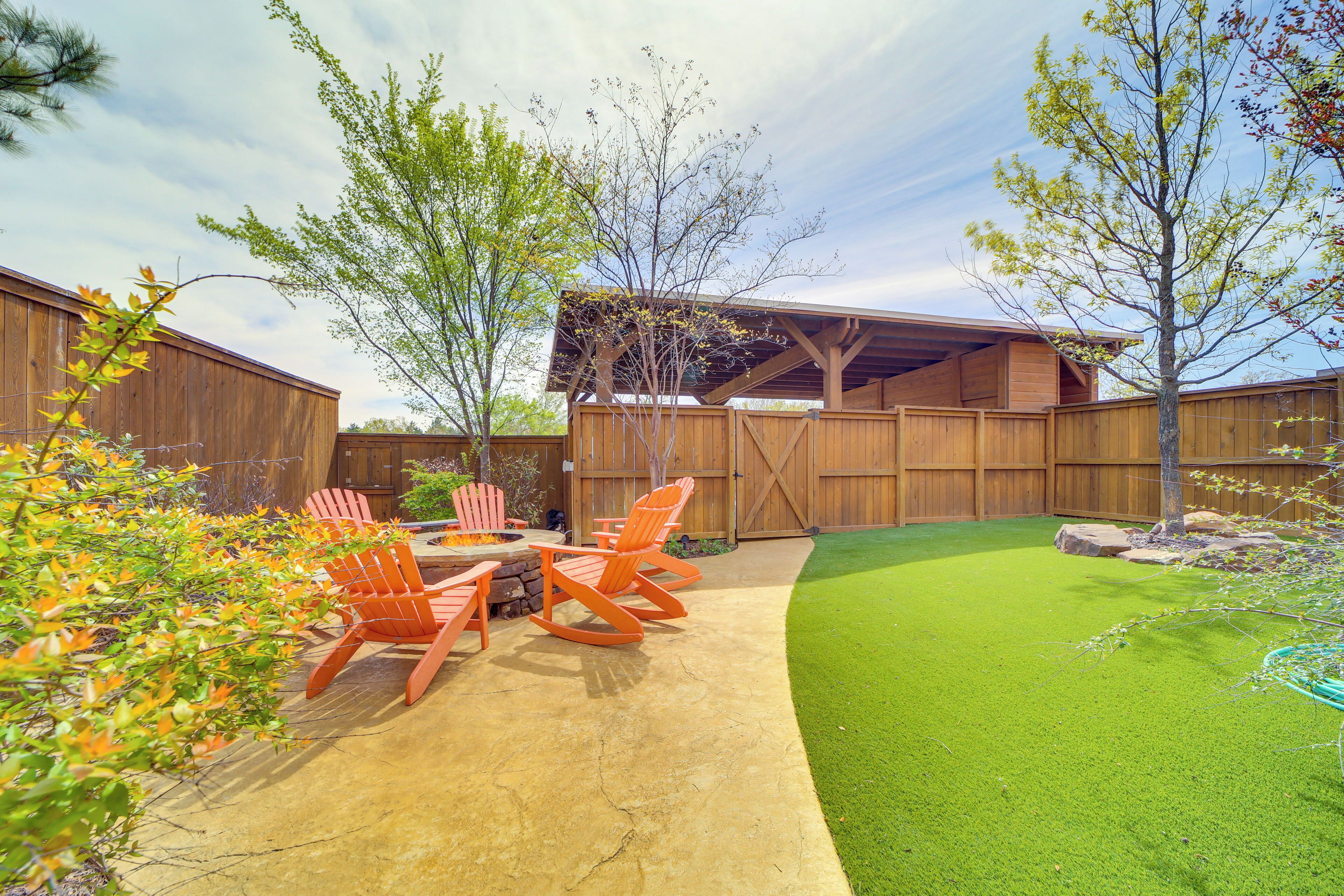 A backyard with a patio, outdoor seating, a wooden fence, and a well-maintained lawn.