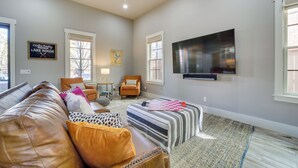 A living room with a leather couch, a striped ottoman, a television mounted on the wall, and a sign that reads "Carlton Landing Lake House". - Carlton Landing Retreat w/ Eufaula Lake Access! (Eufaula)