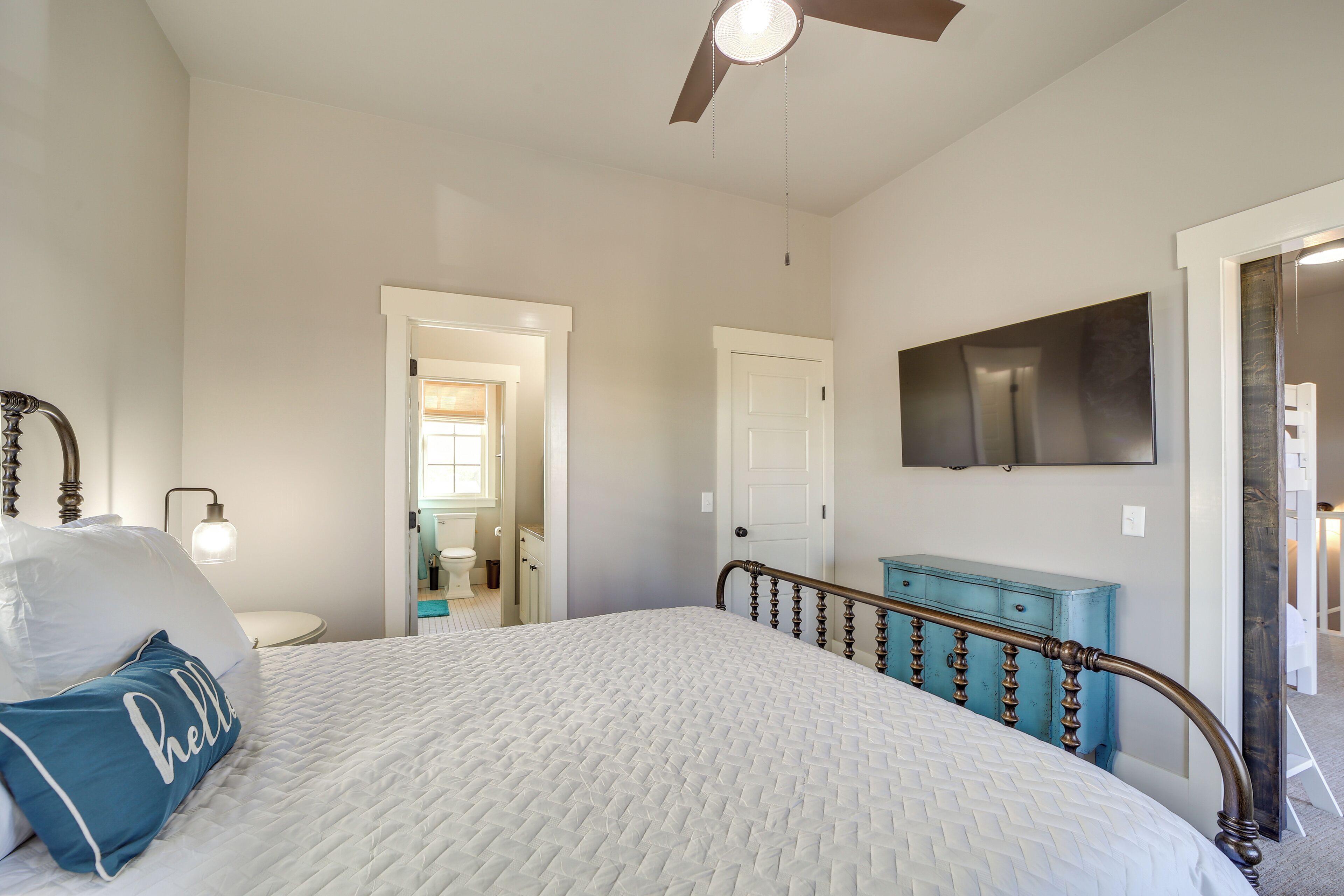 Een slaapkamer met een bed, een plafondventilator, een dressoir en een televisie aan de muur.